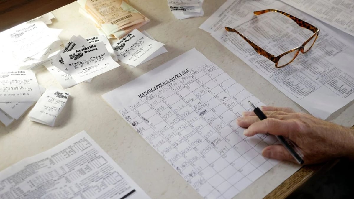 What is a Yankee Bet & How Does it Work? Hand holding a pen surrounded by slips of wagers